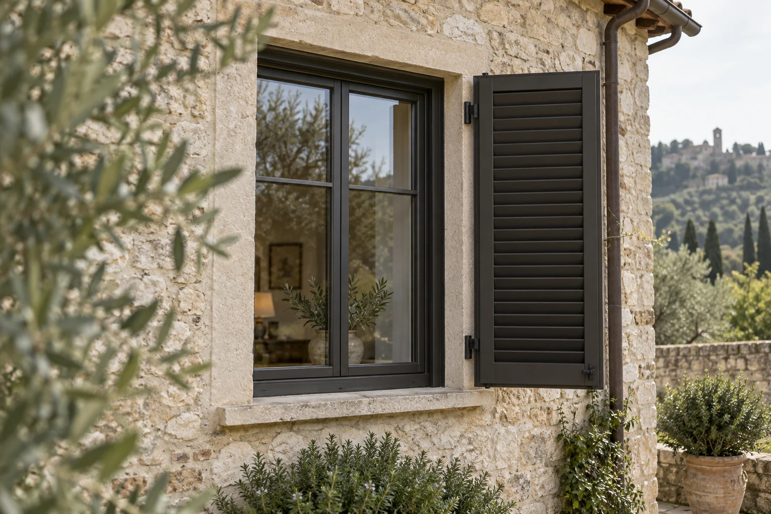 Finestra in alluminio scuro con persiana su una casa in pietra